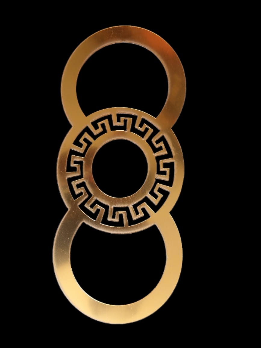 A circular shaped acrylic piece with a geometric design in the center, predominantly gold in color against a black background.