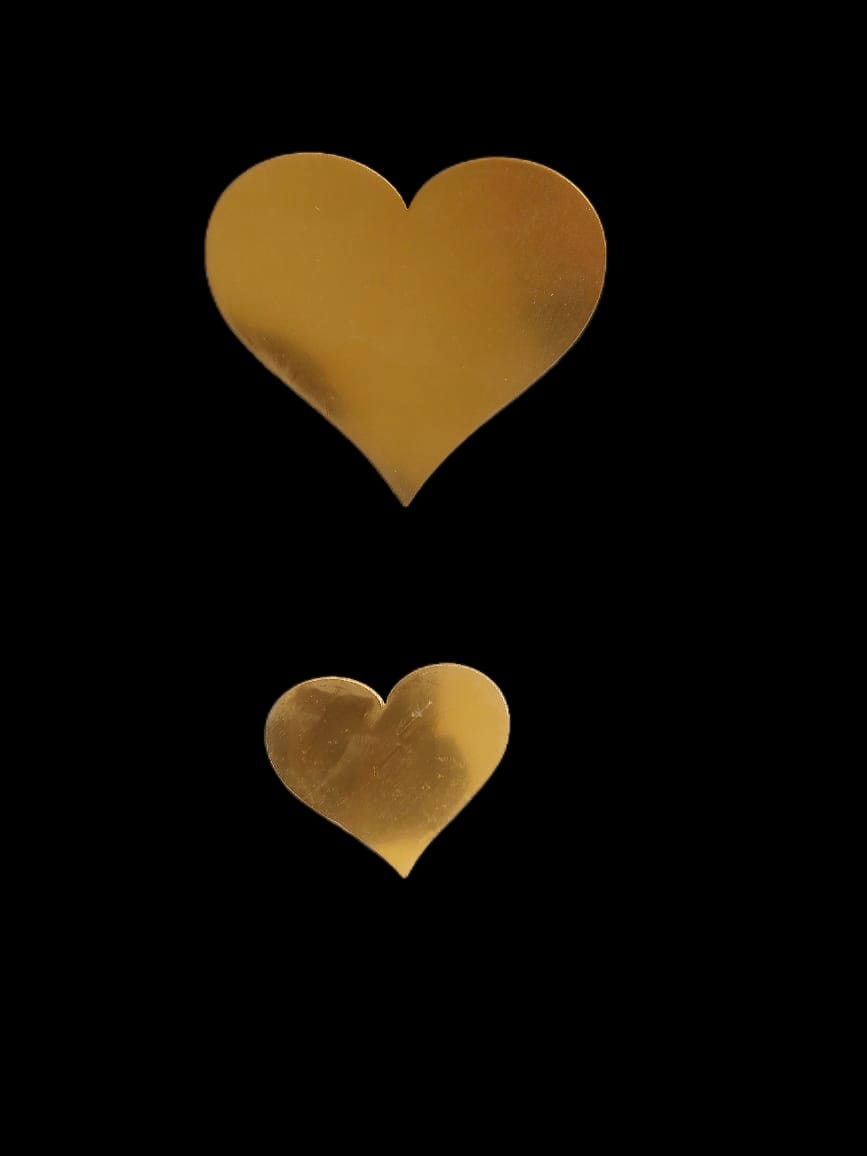 Two gold-colored heart-shaped acrylics of different sizes placed against a black background.