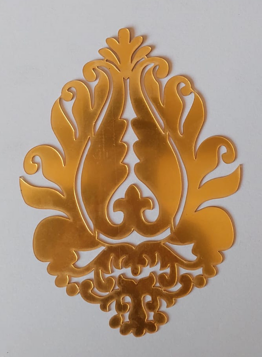 A gold-colored acrylic leaf-shaped decoration mounted on a white background