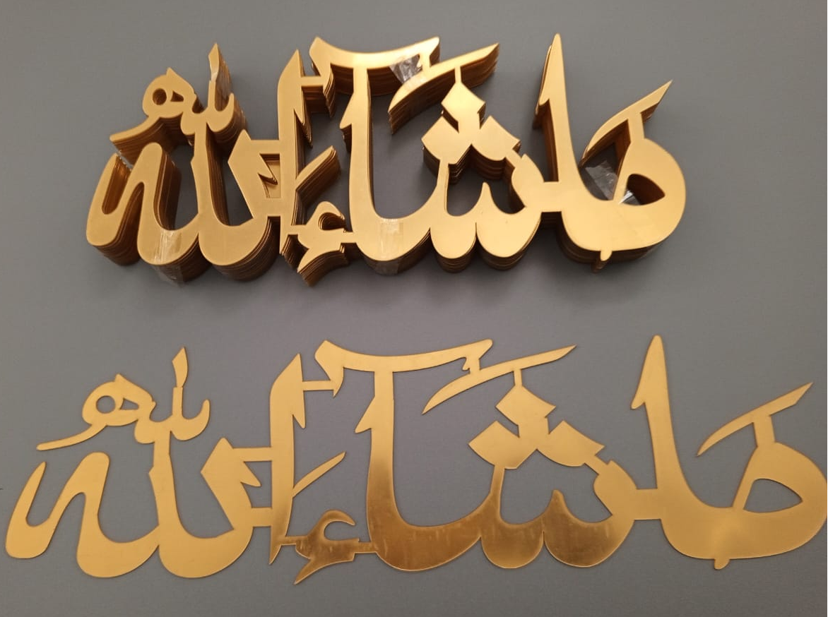 Two Masha Allah-shaped acrylic letters in gold color, displayed against a dark background.